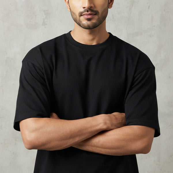 Close-up of the thick, structured fabric of a black oversized cotton t-shirt on a South Asian man, highlighting its heavy wei